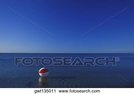 Stock Image - Beach ball in the sea, Cape Cod, Massachusetts, USA . Fotosearch