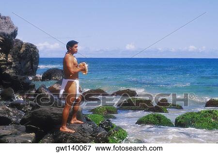 Side profile of a young man standing on a rock and holding a conch shell, Hawaii, USA View Large Photo Image Stock Photo - Side profile of a young man standing on a rock and holding a conch shell, Hawaii, USA. Fotosearch