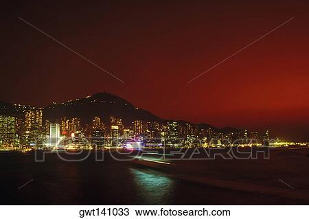 Stock Image - Buildings at the waterfront lit up at night, Hong Kong, China. Fotosearch