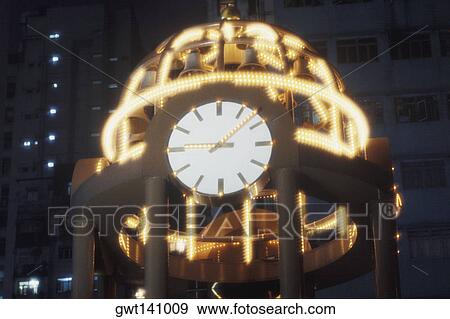 Stock Photo - High section view of a clock tower lit up at night, Hong Kong, China. Fotosearch