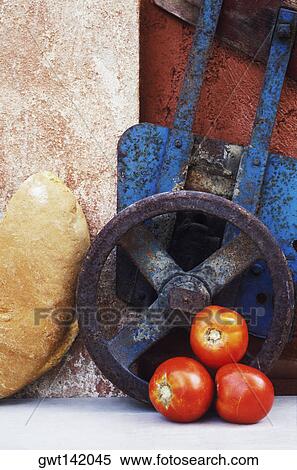 Stock Photography - Close-up of three tomatoes near a wheel and a piece of bread. Fotosearch