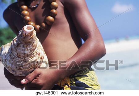 Stock Image - Close-up of a person's hand holding a conch shell, Hawaii, USA. Fotosearch