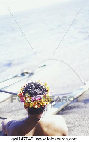 Stock Photo - Rear view of a man sitting on the beach, Hawaii, USA. Fotosearch