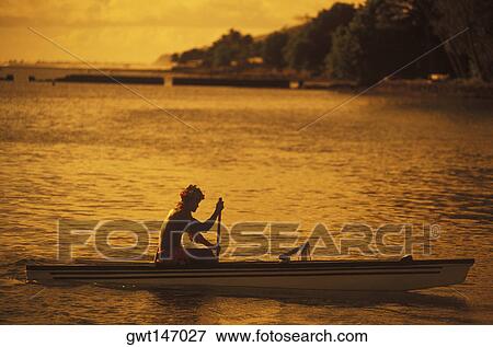 Stock Photo - Silhouette of a person rowing a boat at dusk, Hawaii, USA. Fotosearch