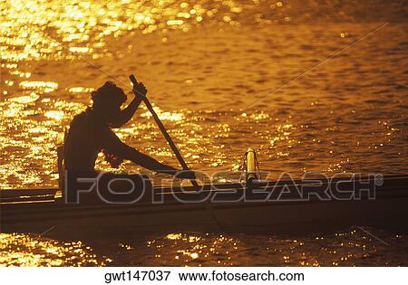 Stock Photo - Silhouette of a person rowing a boat at dusk, Hawaii, USA. Fotosearch
