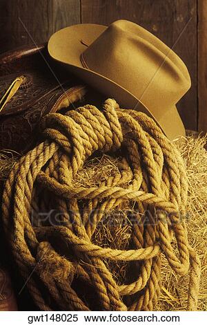 Stock Photography - Close-up of a cowboy hat and lasso on hay. Fotosearch