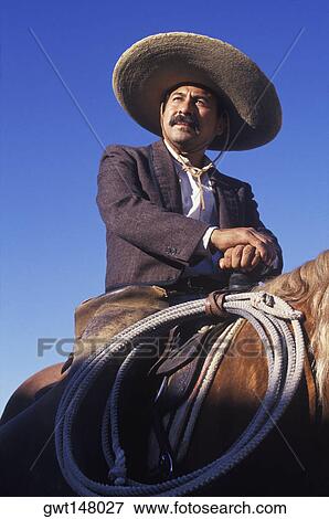 Low angle view of a cowboy sitting on a horse View Large Photo Image Stock Photo - Low angle view of a cowboy sitting on a horse. Fotosearch