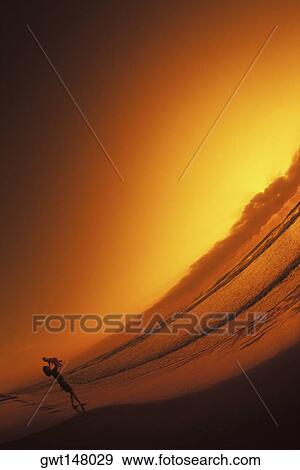 Stock Photo - Silhouette of a woman lifting a baby on the beach, Texas, USA. Fotosearch