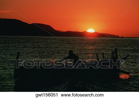 Stock Image - Silhouette of a fisherman on a fishing boat, Malaga, Spain. Fotosearch