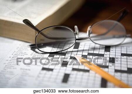 Stock Image - Close-up of a pencil and a pair of eyeglasses on a crossword puzzle. Fotosearch