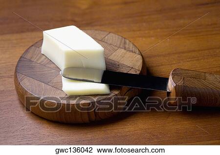 Stock Image - Close-up of a knife with butter and a cutting board. Fotosearch