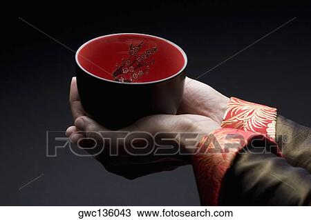 Stock Image - Close-up of a person's hands holding a bowl. Fotosearch