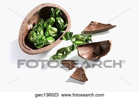 Stock Image - High angle view of broken chocolate egg with sweets. Fotosearch