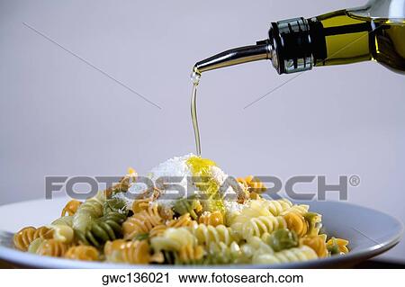 Olive oil being poured on a plate of pasta View Large Photo Image Stock Image - Olive oil being poured on a plate of pasta. Fotosearch