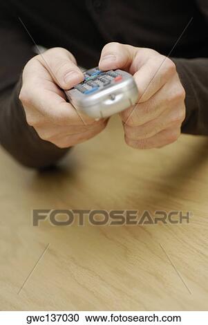Stock Image - Close-up of a man's hand operating a remote control. Fotosearch