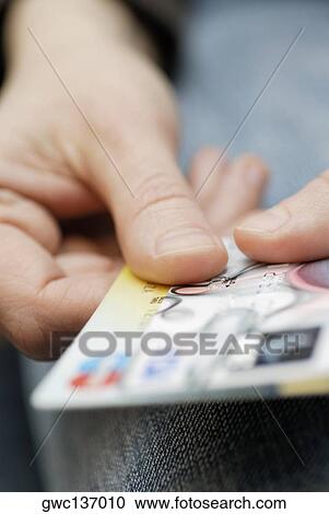 Stock Image - Close-up of a person's hand holding a credit card. Fotosearch