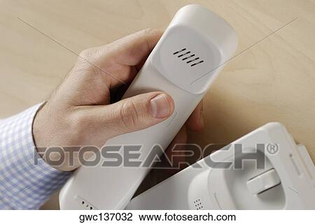 Stock Image - Close-up of a person's hand holding a telephone receiver. Fotosearch