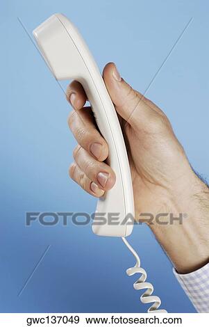 Stock Photo - Close-up of a person's hand holding a telephone receiver. Fotosearch