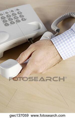 Stock Photo - Close-up of a person's hand holding a telephone receiver. Fotosearch