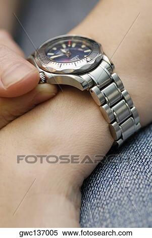 Stock Photography - Close-up of a person's hand holding a wristwatch. Fotosearch