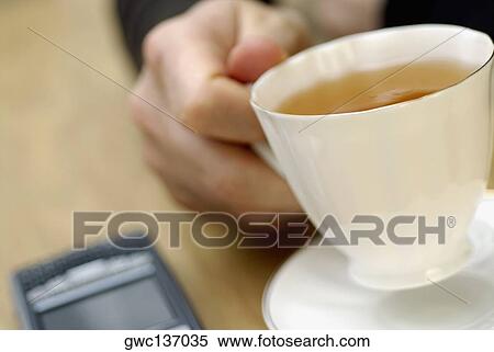 Close-up of a person's hand holding a cup of tea View Large Photo Image Stock Photography - Close-up of a person's hand holding a cup of tea. Fotosearch