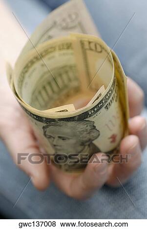 Stock Photo - Close-up of a person's hand holding American dollar bills. Fotosearch