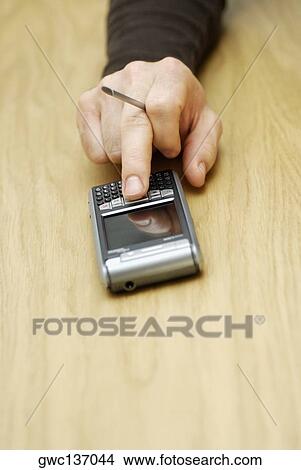 Picture - Close-up of a person's hand operating a mobile phone. Fotosearch