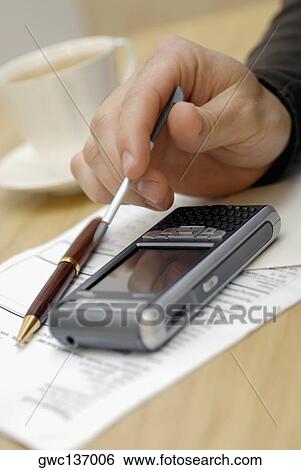 Stock Photograph - Close-up of a person's hand operating a personal data assistant. Fotosearch