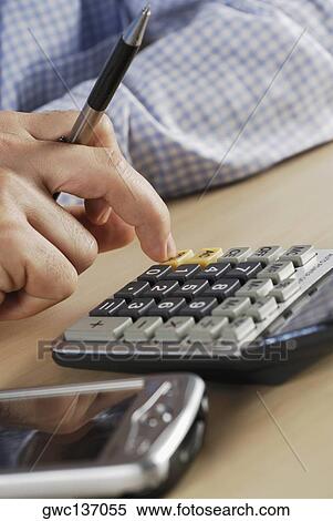 Stock Photography - Close-up of a person's hand using a calculator. Fotosearch
