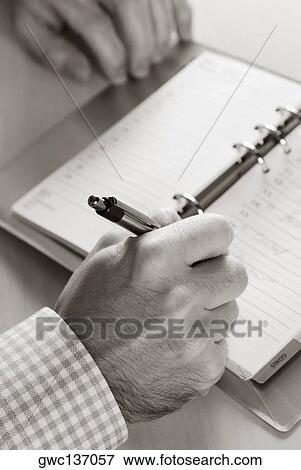 Stock Photo - Close-up of a person's hand writing in a diary. Fotosearch