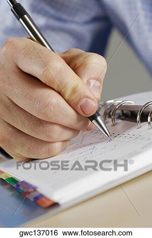 Close-up of a person's hand writing in a diary View Large Photo Image Stock Photograph - Close-up of a person's hand writing in a diary. Fotosearch