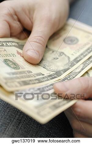 Stock Photo - Close-up of a person's hands holding American dollar bills. Fotosearch