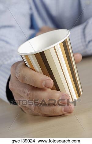 Picture - Close-up of a person's hand holding a disposable cup. Fotosearch