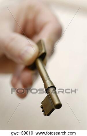 Stock Image - Close-up of a person's hand holding a key. Fotosearch