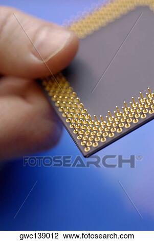 Stock Image - Close-up of a person's hand holding a computer chip. Fotosearch