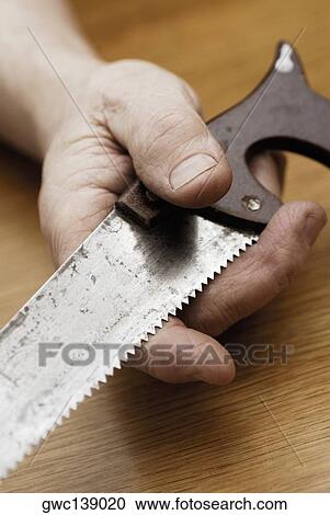 Stock Image - Close-up of a person's hand holding a saw. Fotosearch