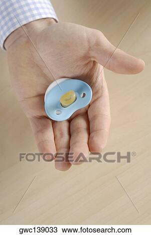 Close-up of a person's hand holding a pacifier View Large Photo Image Stock Image - Close-up of a person's hand holding a pacifier. Fotosearch