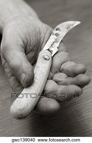 Stock Image - Close-up of a person's hand holding a knife. Fotosearch