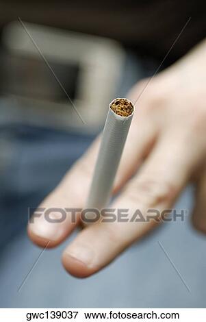 Stock Photo - Close-up of a person's hand holding a cigarette. Fotosearch