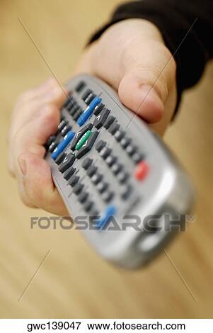 Stock Photo - Close-up of a person's hand holding a remote control. Fotosearch