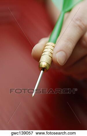 Stock Photo - Close-up of a person's hand holding a dart. Fotosearch