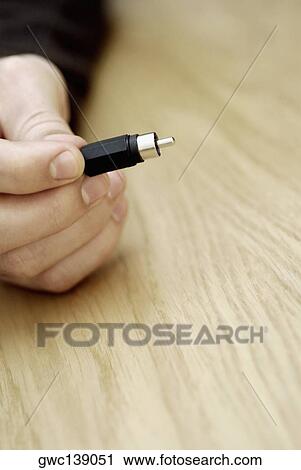 Stock Image - Close-up of a person's hand holding an electrical plug. Fotosearch
