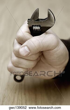 Close-up of a person's hand holding an adjustable wrench View Large Photo Image Stock Image - Close-up of a person's hand holding an adjustable wrench. Fotosearch