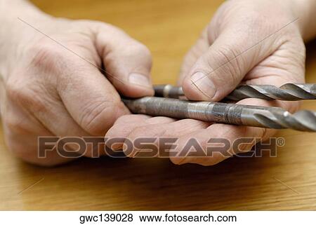 Stock Photo - Close-up of a person's hand holding drill bits. Fotosearch