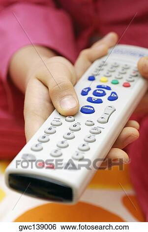Stock Photograph - Close-up of a person's hand using a remote control. Fotosearch