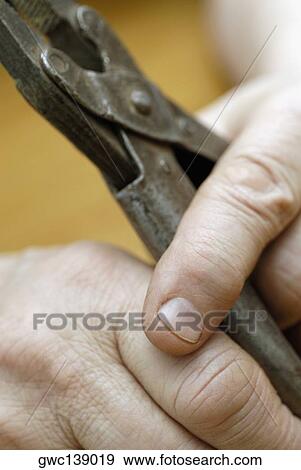 Stock Photo - Close-up of a person's hands holding a pair of pliers. Fotosearch