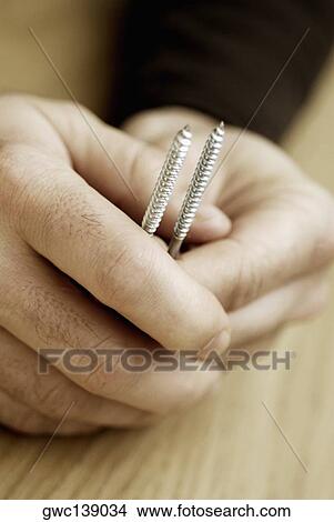 Picture - Close-up of a person's hands holding two screws. Fotosearch