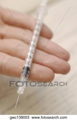 Stock Image - Close-up of a syringe on a person's hand. Fotosearch