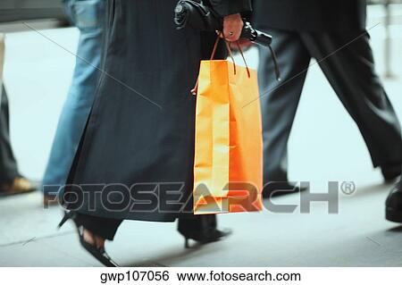 Low section view of a person carrying a shopping bag View Large Photo Image Stock Photograph - Low section view of a person carrying a shopping bag. Fotosearch