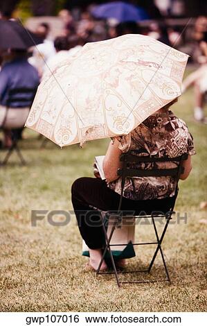 Rear view of a woman reading a book View Large Photo Image Stock Photograph - Rear view of a woman reading a book. Fotosearch